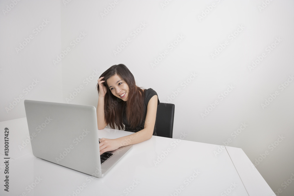 Smiling young businesswoman working on laptop at office desk Smiling young businesswoman working on laptop at office desk