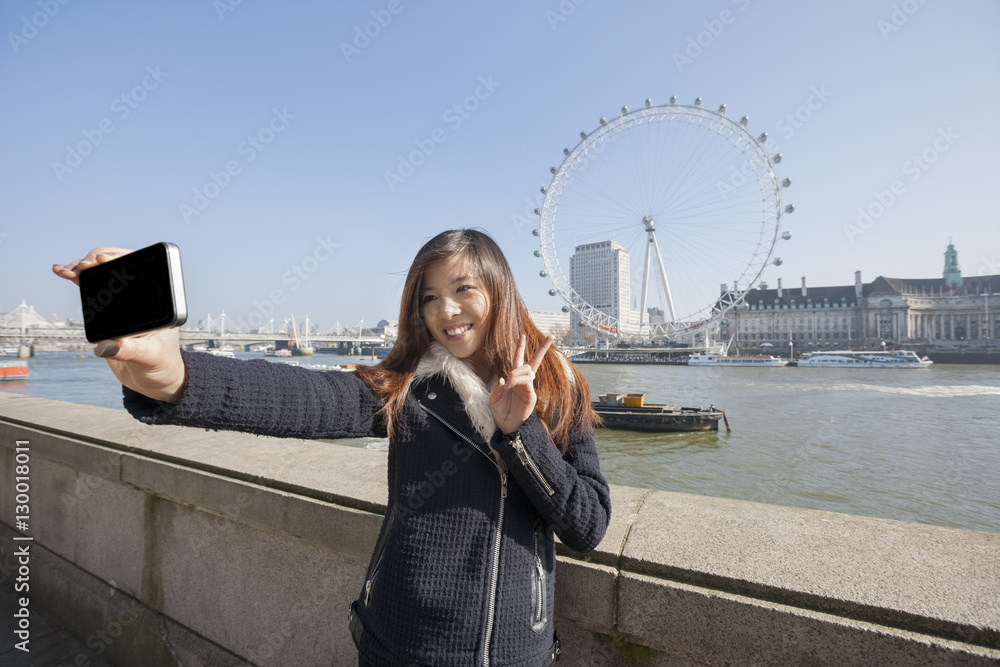 Φωτογραφία Happy woman taking self portrait through cell phone against London Eye at London