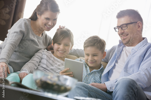 Happy family using digital tablet together in living room © moodboard