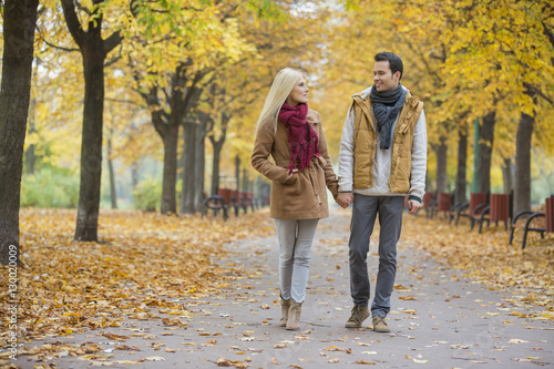 Couple holding hands while walking in park during autumn © moodboard