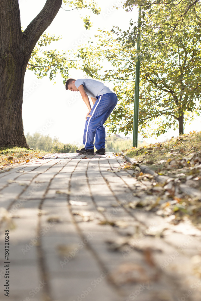 Fototapeta premium Full length of tired young man standing on path after running in park