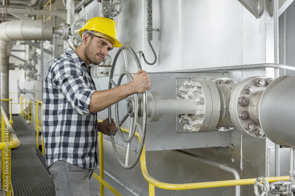 Industrial worker turning large valve Industrial worker turning large valve