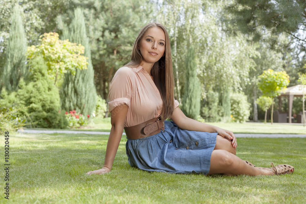 Portrait of attractive young woman sitting on grass in park Portrait of attractive young woman sitting on grass in park