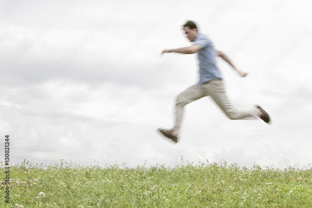 Blurred motion of young man jumping in park against sky Blurred motion of young man jumping in park against sky