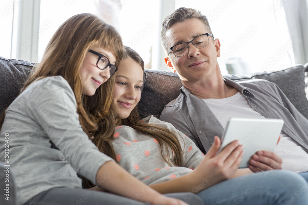 Father and daughters using tablet PC on sofa at home Father and daughters using tablet PC on sofa at home