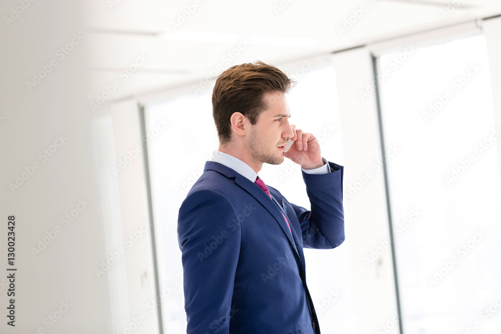 Side view of young businessman using mobile phone in new office Side view of young businessman using mobile phone in new office