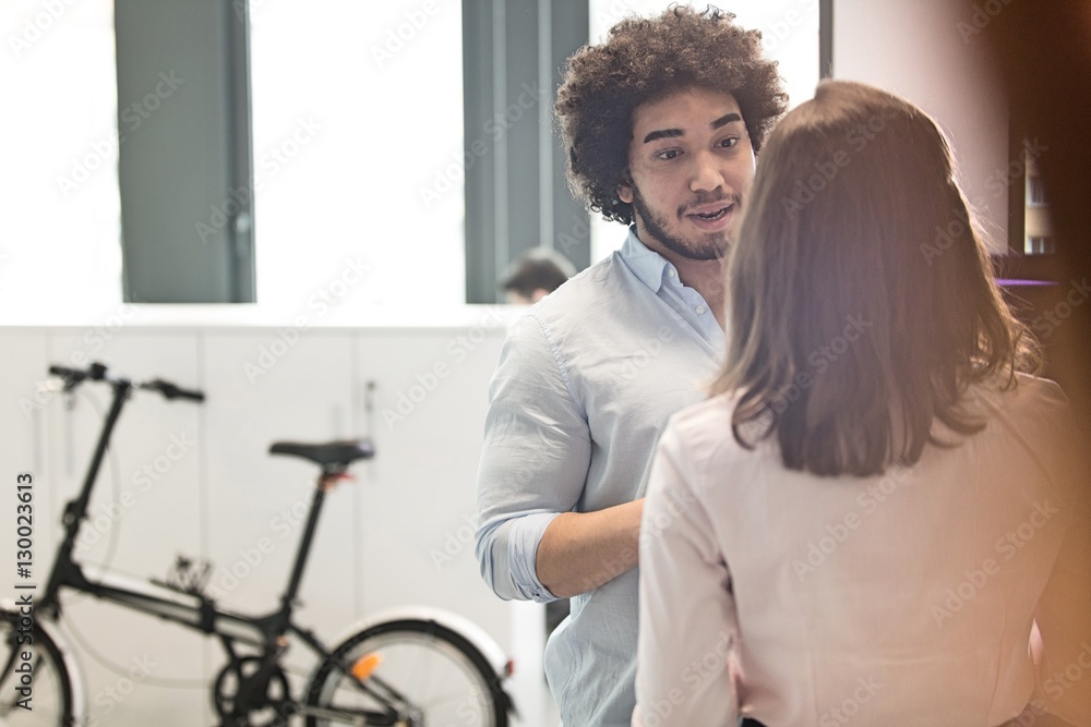 Young businessman talking with female colleague in office Young businessman talking with female colleague in office