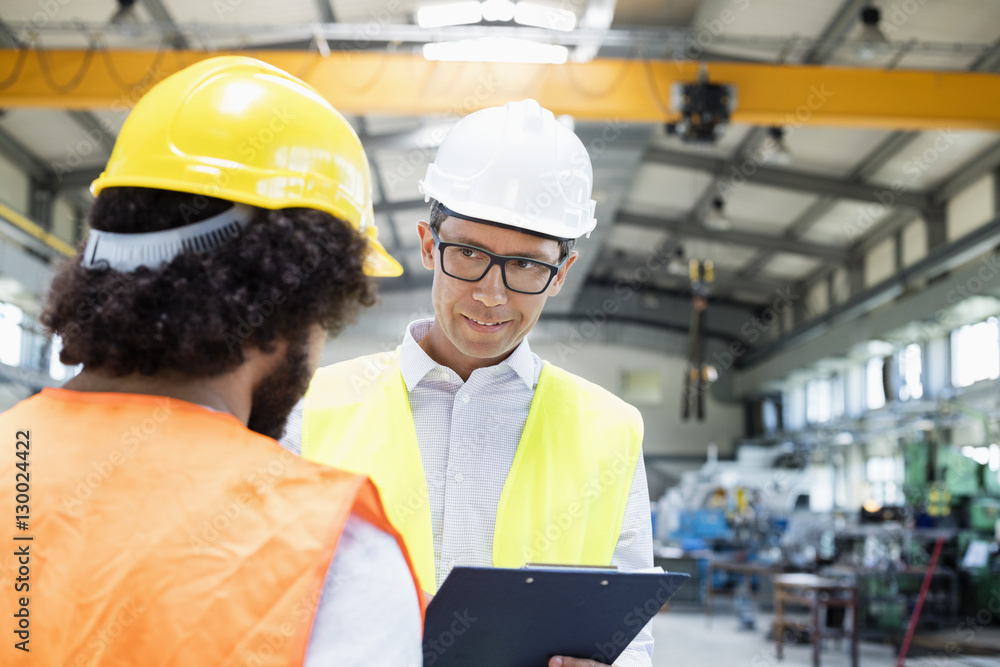 Male supervisor discussing with manual worker in metal industry Male supervisor discussing with manual worker in metal industry