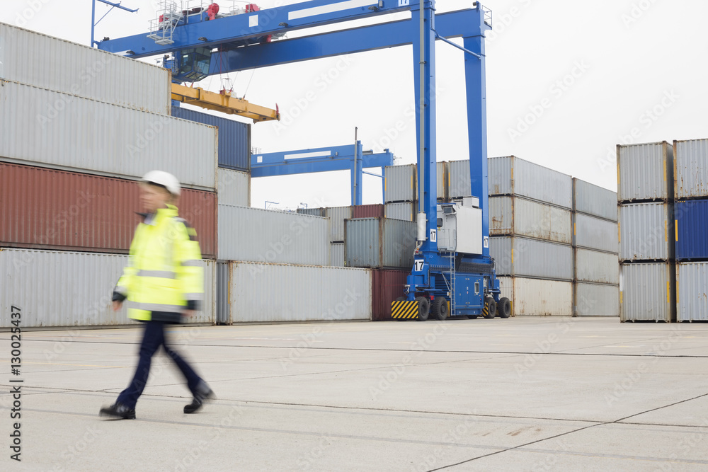 Full-length of female worker walking in shipping yard Full-length of female worker walking in shipping yard