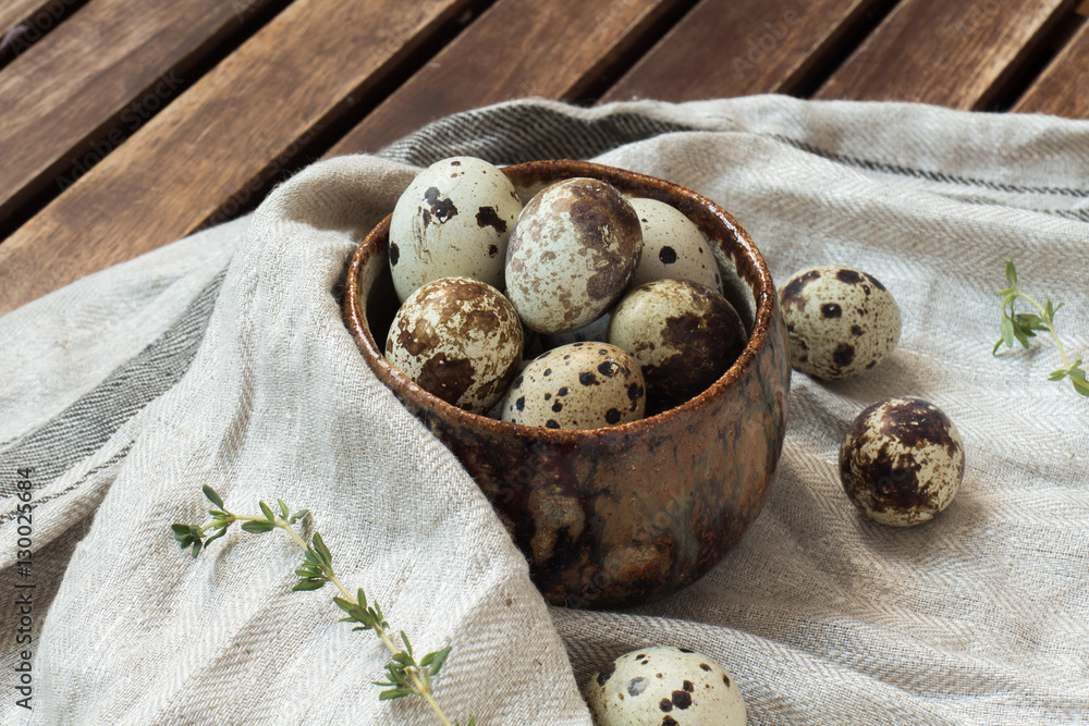 Close up of quail eggs in clay bowl with gray kitchen napkin on brown wooden rustic table background Close up of quail eggs in clay bowl with gray kitchen napkin on brown wooden rustic table background