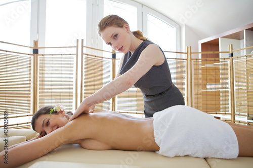 Portrait of young woman receiving massage from masseuse