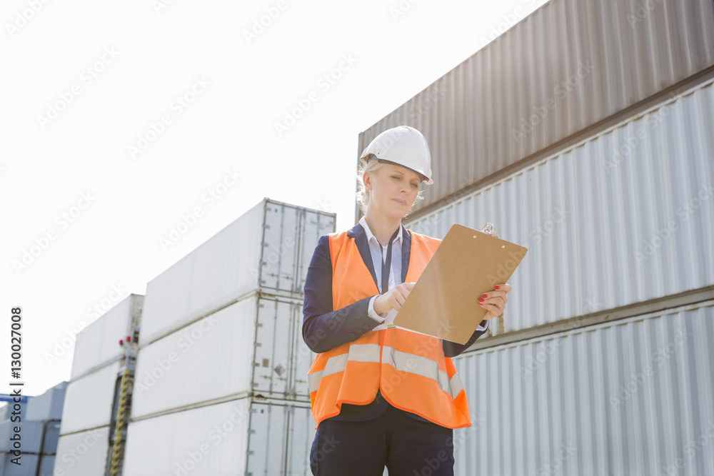 Female worker reading clipboard in shipping yard Female worker reading clipboard in shipping yard