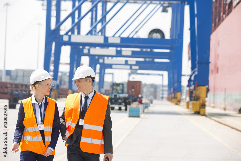 Engineers conversing while walking in shipping yard Engineers conversing while walking in shipping yard