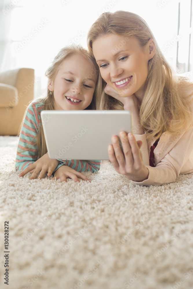 Happy mother and daughter using digital tablet on floor at home Happy mother and daughter using digital tablet on floor at home