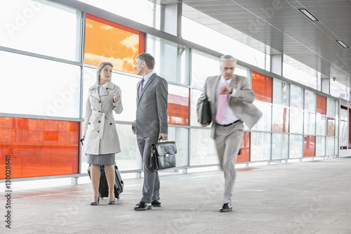 Businesspeople walking while male colleague rushing in railroad station