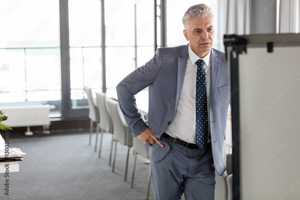 Mature businessman looking at whiteboard in meeting room Mature businessman looking at whiteboard in meeting room