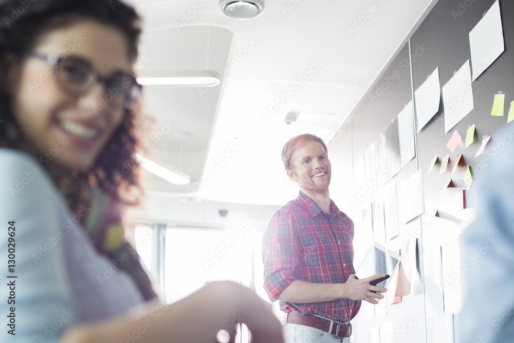 Obraz premium Smiling businessman with female colleague in foreground at creative office