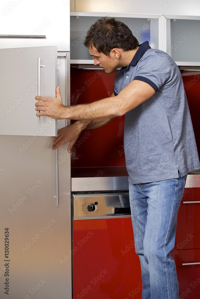 oung man looking in refrigerator