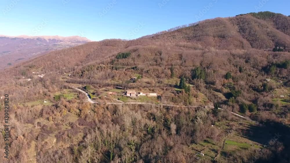 Aerial shot, little village in the middle of an autumn wood in the mountains with orange dry leaves, sun high in the sky, filmed with drone Aerial shot, little village in the middle of an autumn wood in the mountains with orange dry leaves, sun high in the sky, filmed with drone