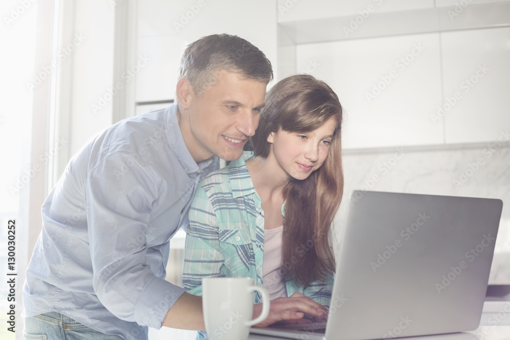 Father and daughter using laptop at home