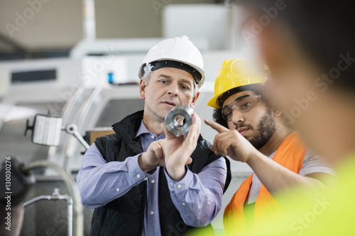 Supervisor and manual worker discussing over metal in industry photo