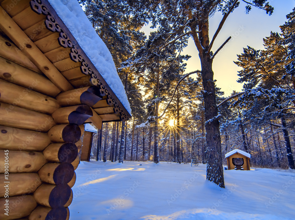 Wooden cabin in winter forest snow sunset