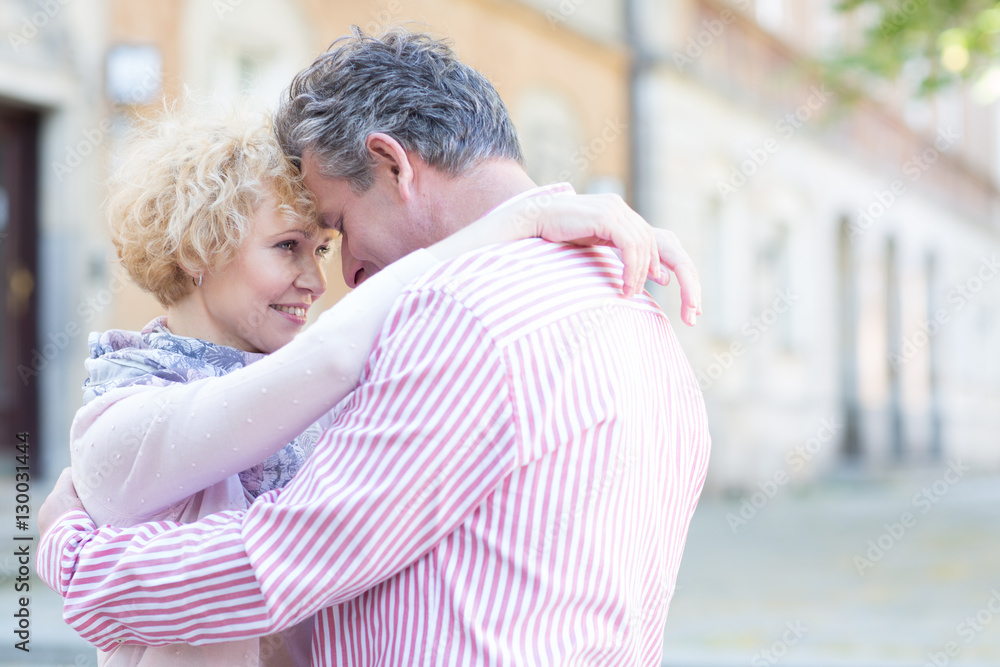 Happy middle-aged couple embracing in city Happy middle-aged couple embracing in city