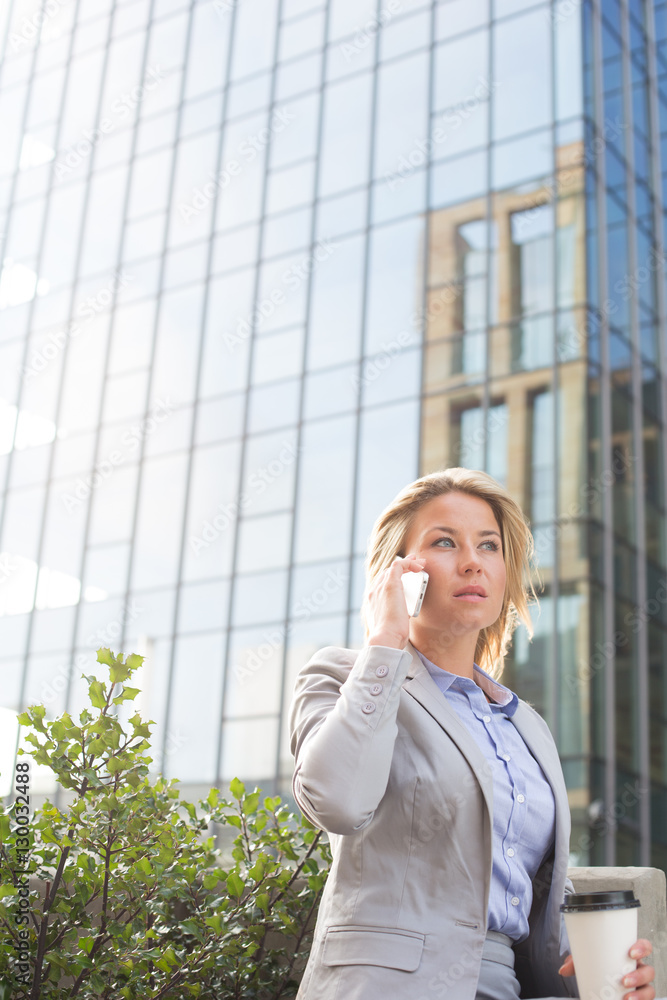 Businesswoman using mobile phone outside office building Businesswoman using mobile phone outside office building