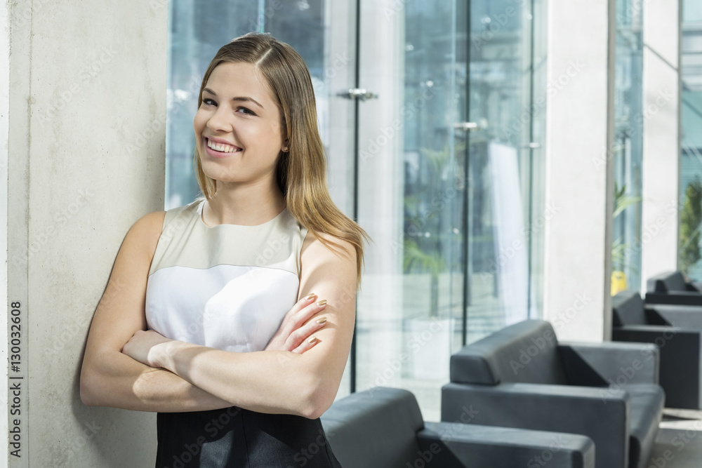 Portrait of happy businesswoman standing arms crossed at office lobby Portrait of happy businesswoman standing arms crossed at office lobby