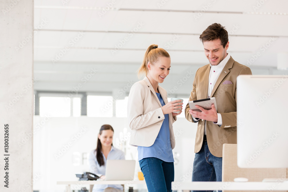 Young businesswoman with male colleague using digital tablet in office