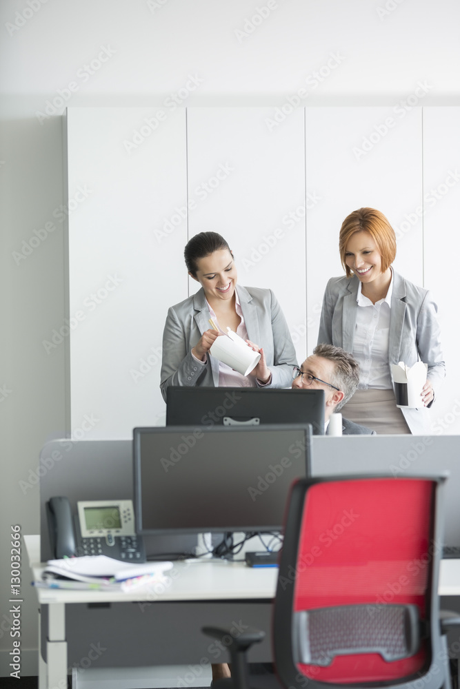 Business people having lunch while using computer in office Business people having lunch while using computer in office