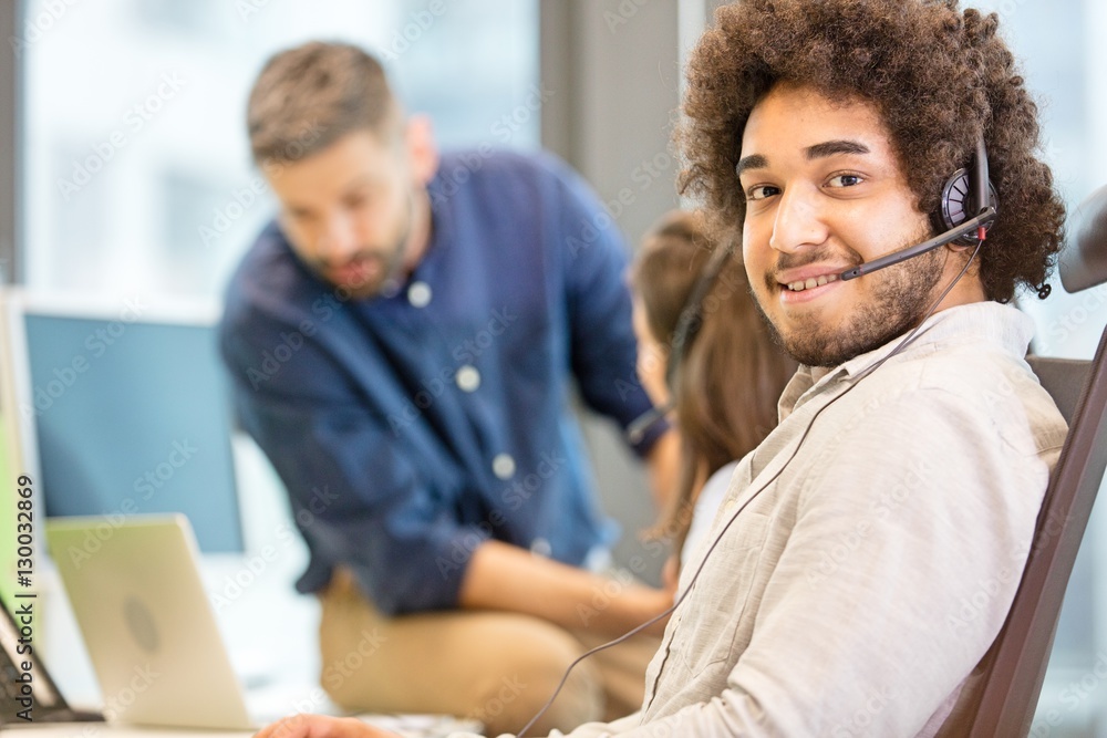 Portrait of confident customer service representative with colleagues in background at office Portrait of confident customer service representative with colleagues in background at office