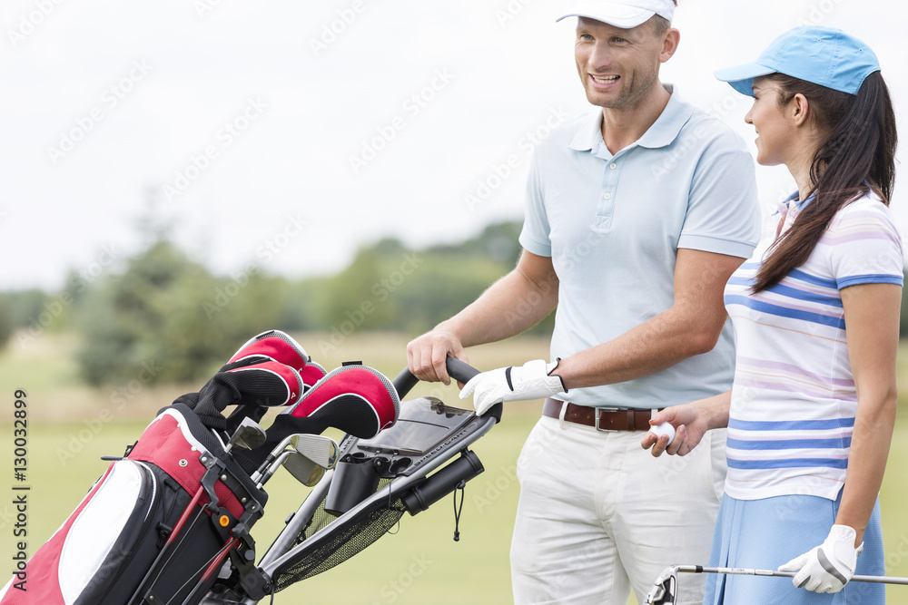 Naklejka premium Happy friends with bag talking at golf course