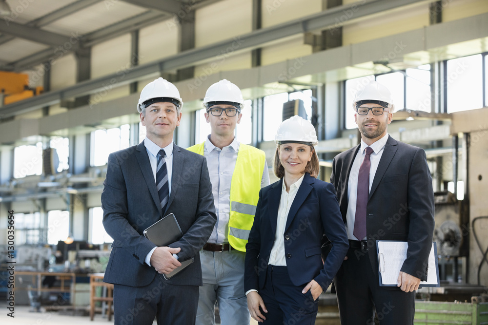 Portrait of confident business people wearing hardhats in metal industry Portrait of confident business people wearing hardhats in metal industry