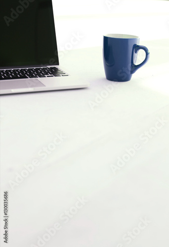 Laptop and coffee cup on white floor of office