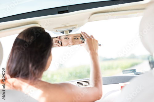 Wallpaper Mural Woman adjusting rearview mirror while using mobile phone in car Torontodigital.ca