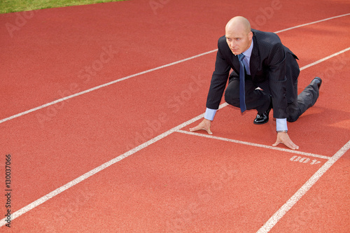 Businessman at the start line of running track