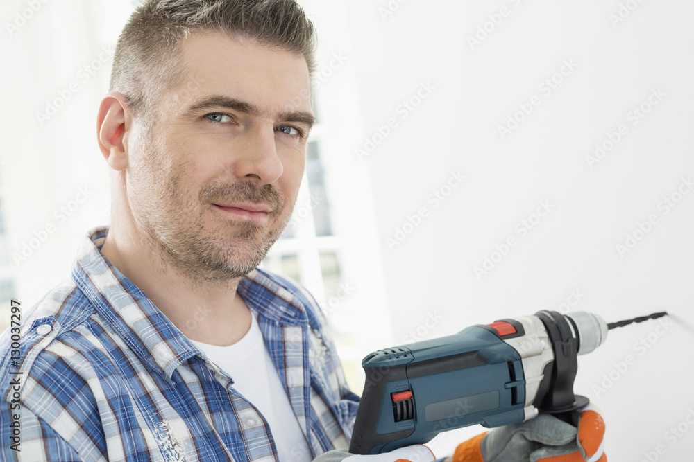Portrait of mid-adult man drilling hole in wall Portrait of mid-adult man drilling hole in wall