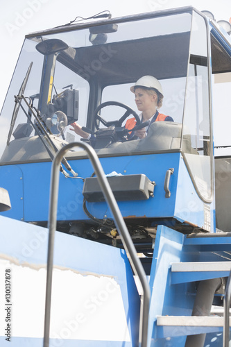Female worker operating forklift truck in shipping yard