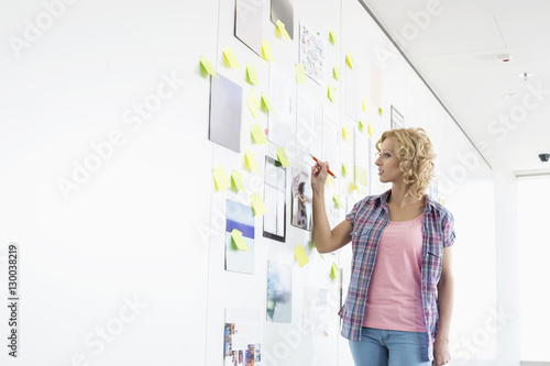 Creative businesswoman writing on sticky paper in office