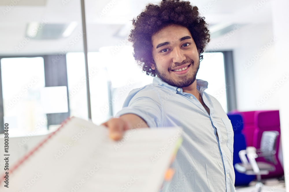 Portrait of smiling young businessman giving document in office Portrait of smiling young businessman giving document in office