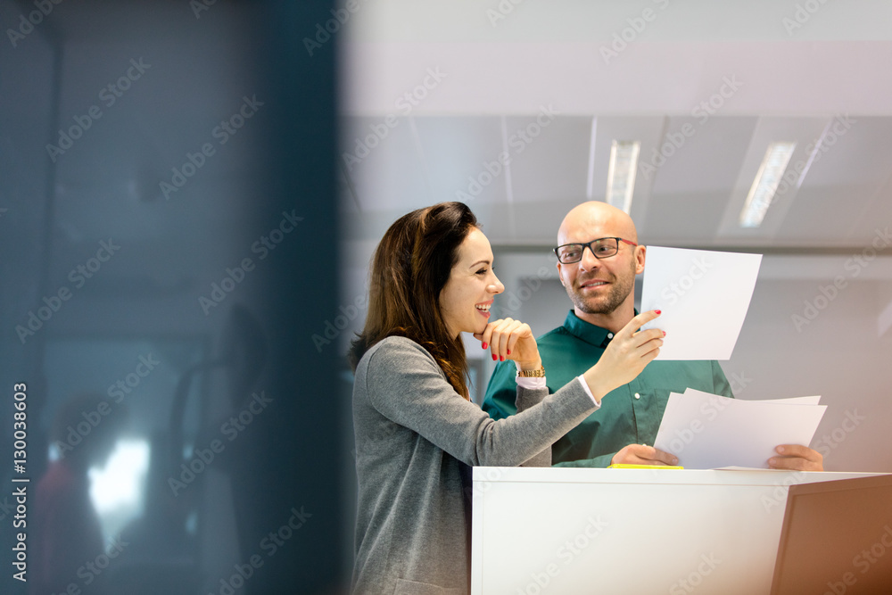 Businessman and businesswoman discussing over documents in office Businessman and businesswoman discussing over documents in office