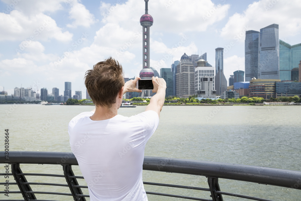 Fototapeta premium Rear view of man photographing Oriental Pearl Tower while standing by railing