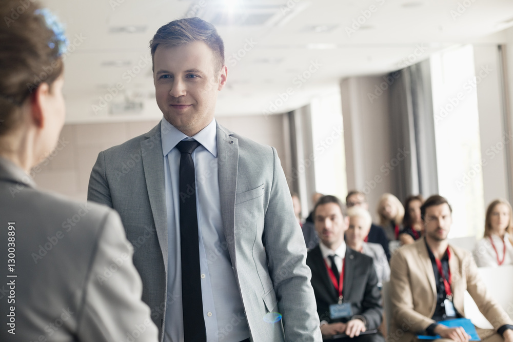 Confident businessman looking at public speaker during seminar Confident businessman looking at public speaker during seminar