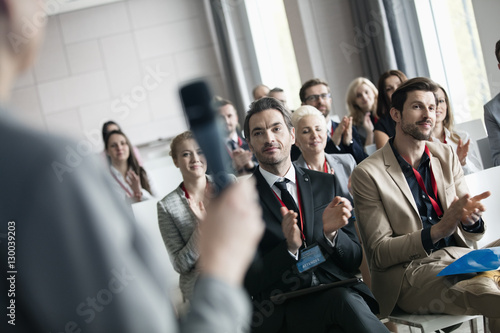 Business people applauding for public speaker during seminar