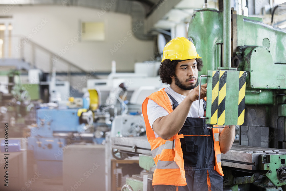Young manual worker operating machinery in metal industry Young manual worker operating machinery in metal industry