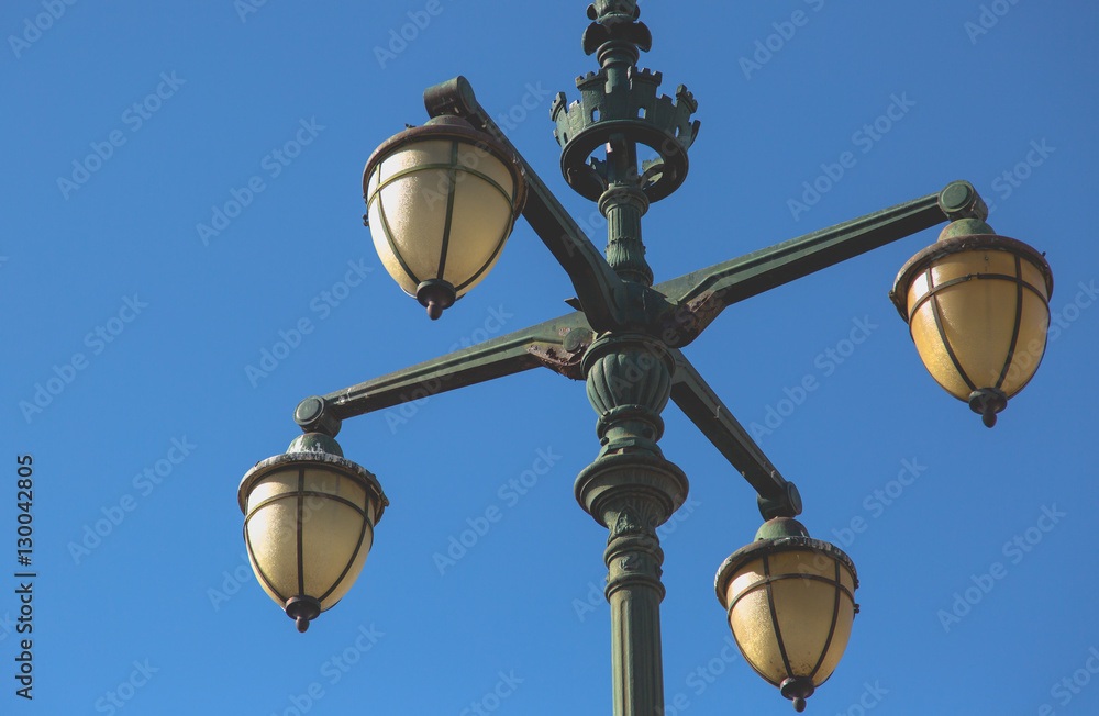 Old vintage street light with four arms on green cast iron poll