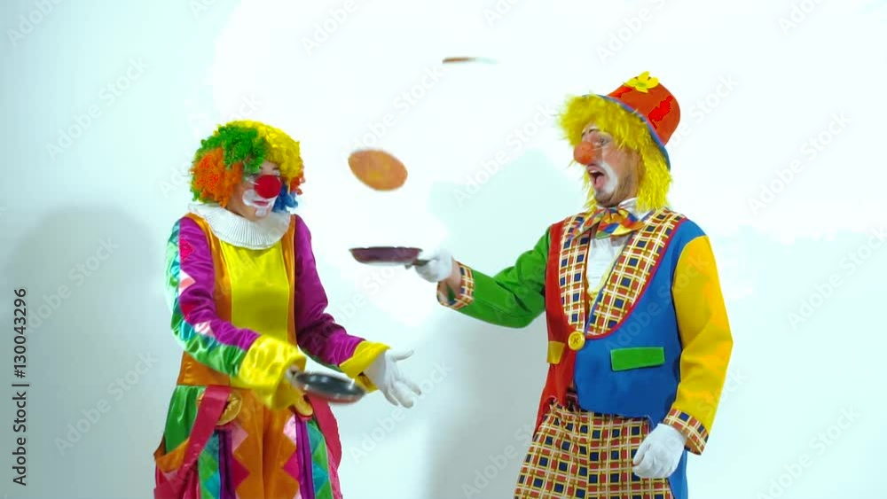 Portrait of two funny clowns playing with pans and false-cakes Portrait of two funny clowns playing with pans and false-cakes