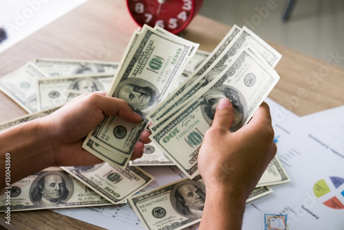 Closeup of Asian male hands counting bunch of dollars banknotes