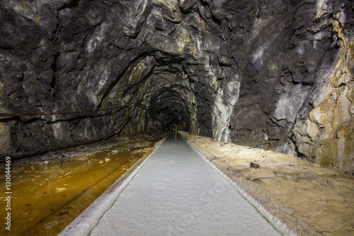 Abandoned old mine ore tunnel with rails and white lime